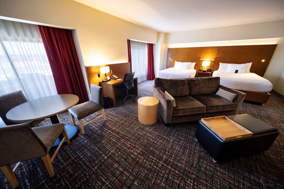 Una habitación de hotel con cama, dos sofás, escritorio, silla y una mesita.