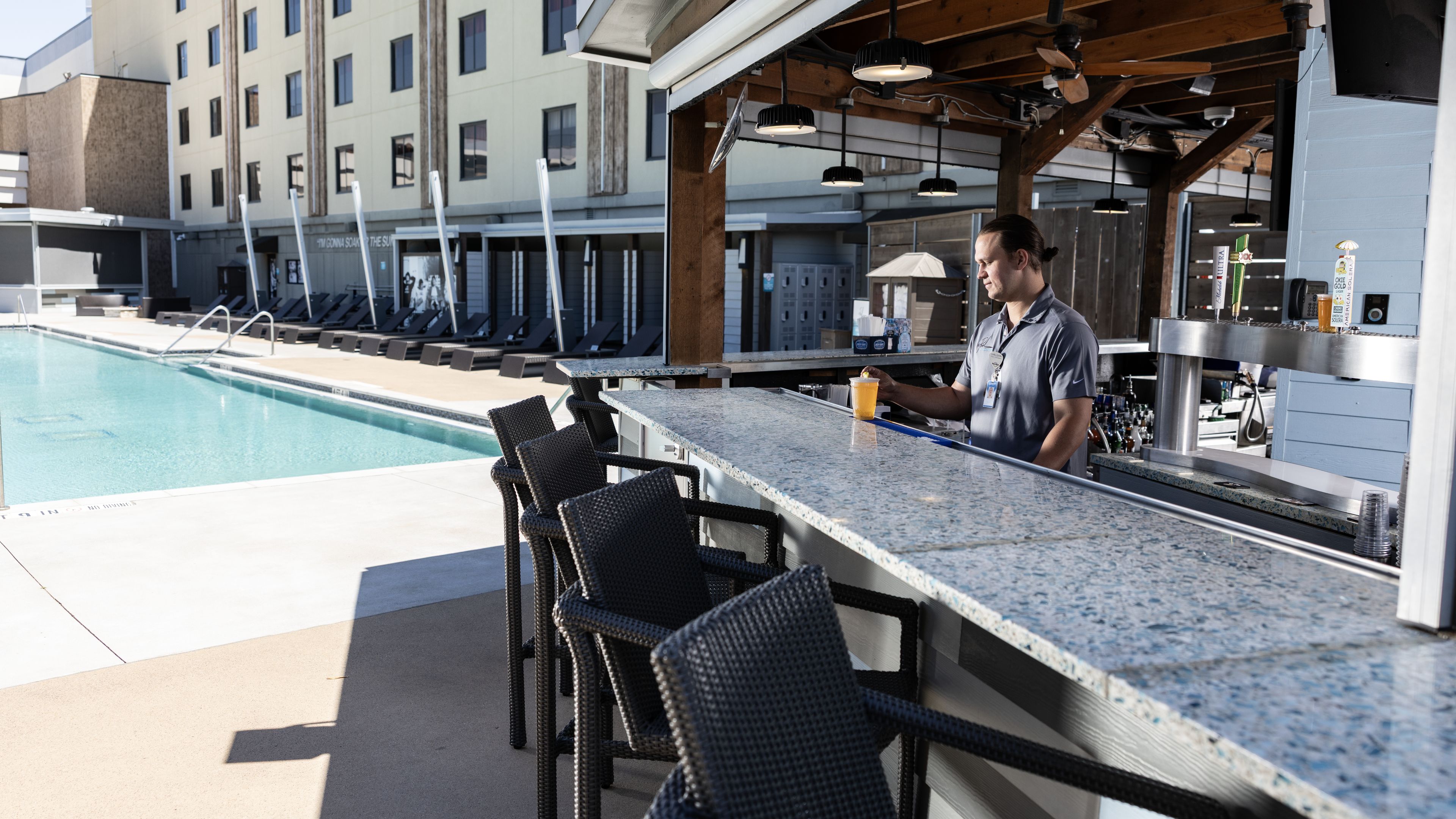 Un bar situé au bord de la piscine, avec des sièges et un barman.
