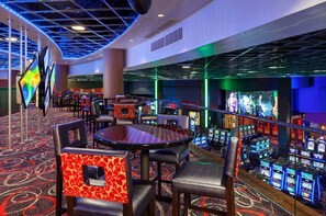 A casino area with gaming tables, chairs, and slot machines. - Hard Rock Hotel and Casino Tulsa (Catoosa)