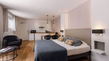 Una habitación de hotel moderna con una cama grande, un escritorio y una kitchenette.