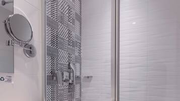 A modern bathroom with a glass shower enclosure, a white sink, and a patterned wall.