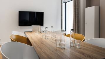 Een moderne eethoek met een houten tafel, helder servies en witte en gele stoelen.