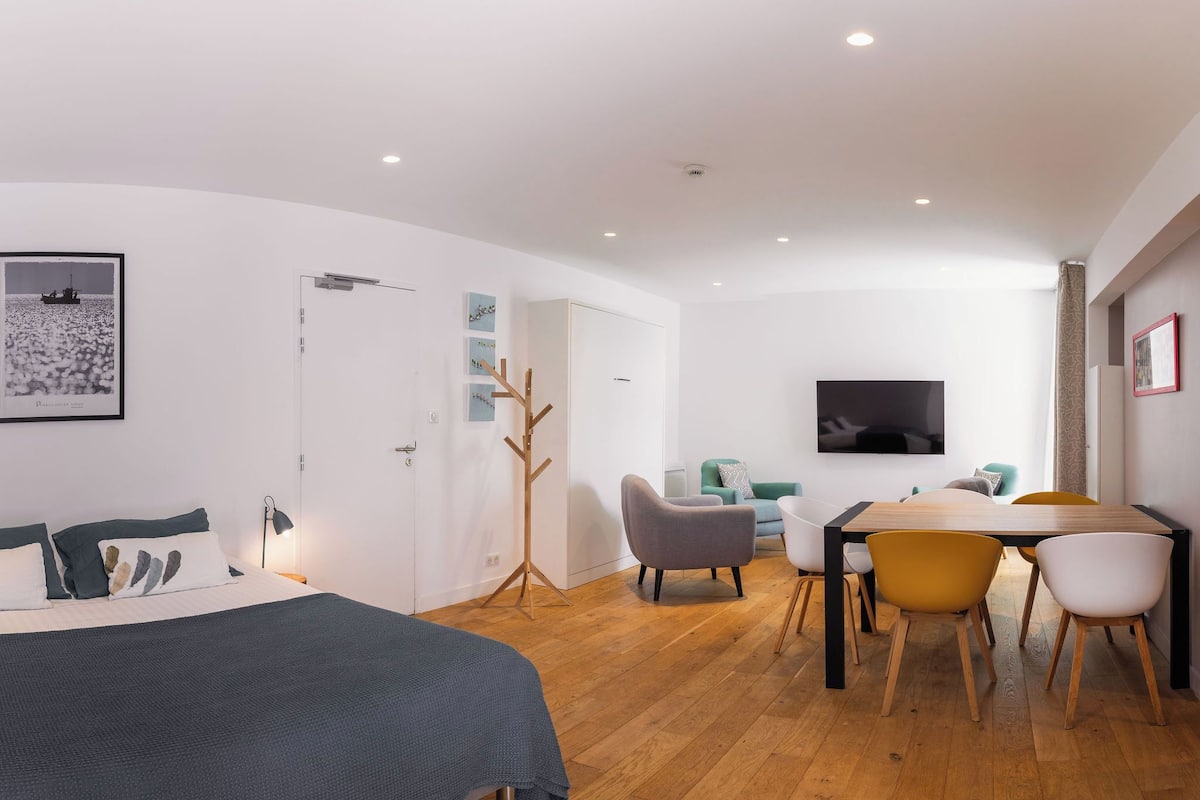 A modern bedroom with a bed, a desk, and a TV.