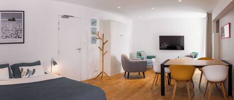 A modern bedroom with a bed, a desk, and a TV.