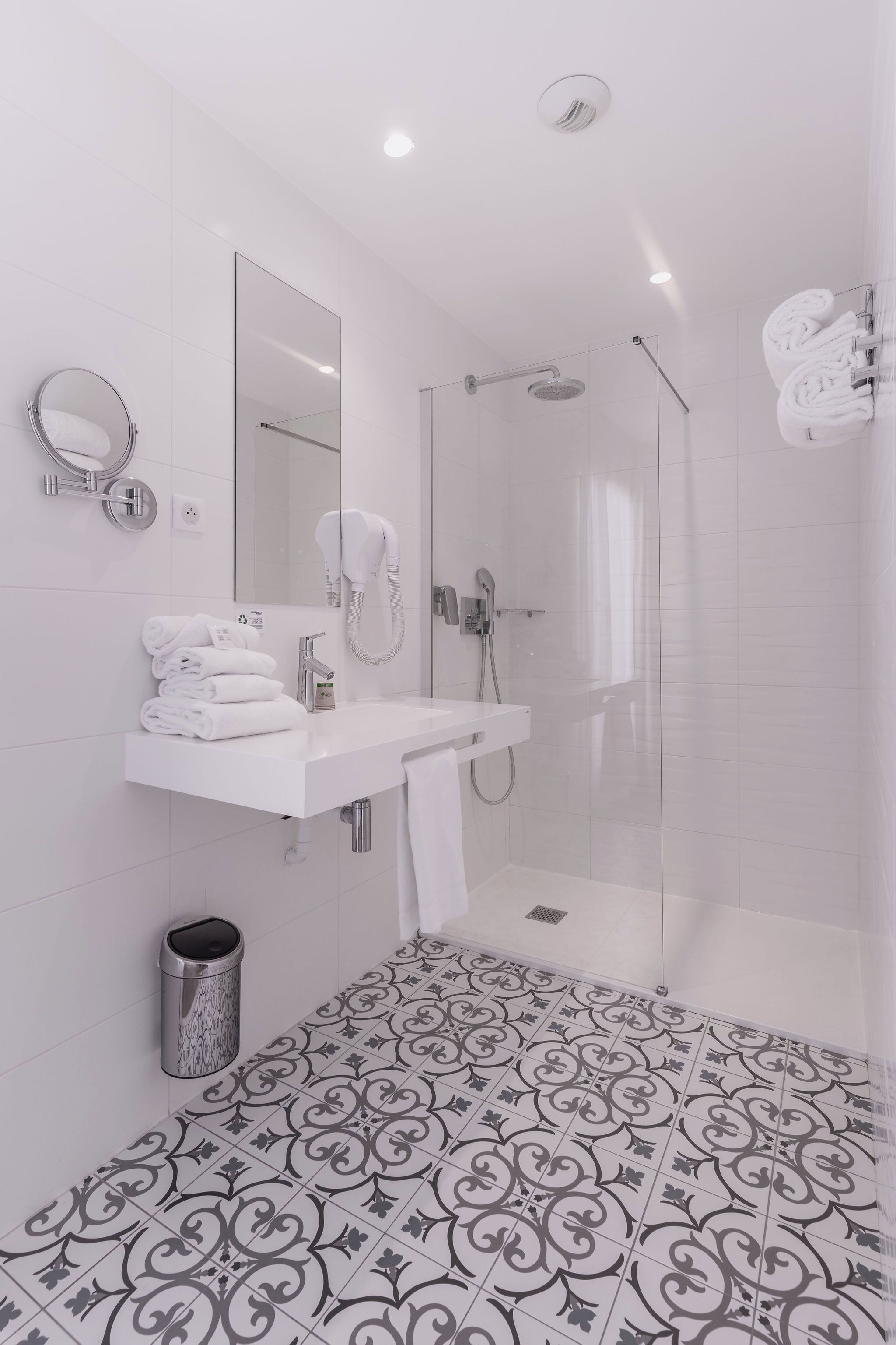 Un baño moderno con un lavabo, espejo y ducha blancos.