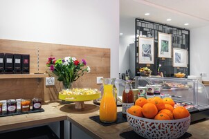 Un buffet de petit-déjeuner proposant divers aliments, un vase rempli de fleurs et une carafe de jus.