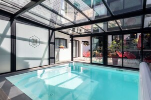 Une piscine intérieure moderne avec des murs en verre, un logo bien visible et des espaces de détente en plein air.