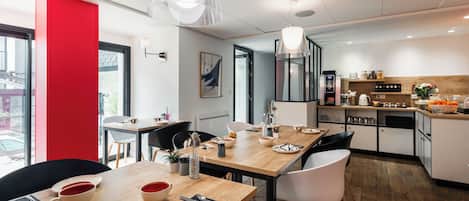 Un comedor moderno con una mesa de madera, sillas negras y blancas, y una pared de acento roja.