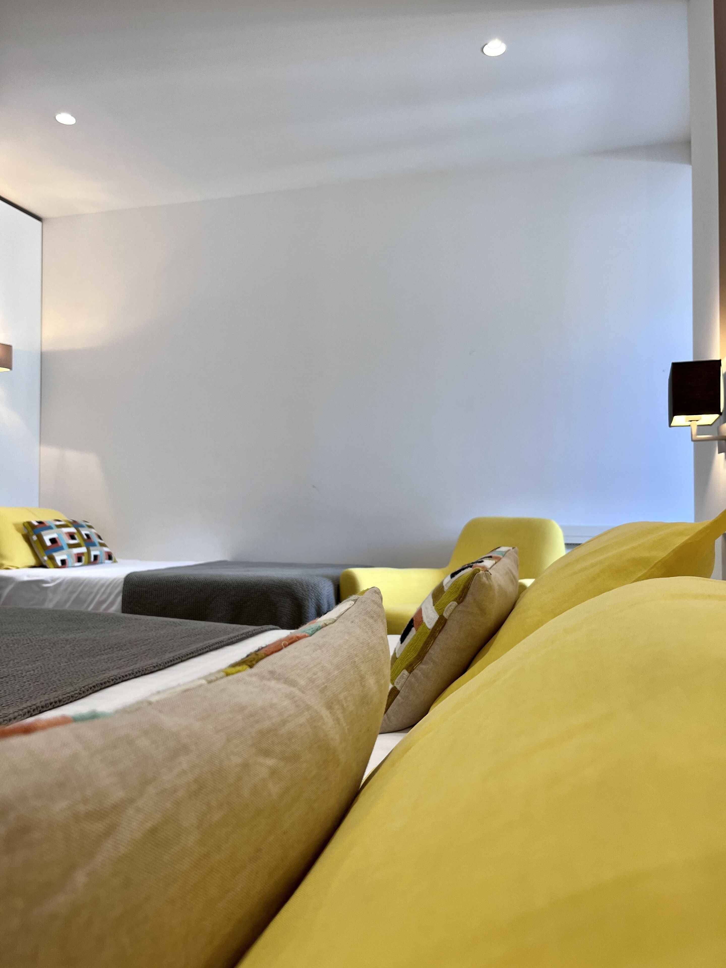 A hotel room with a bed, a chair, and a flat-screen TV mounted on the wall.