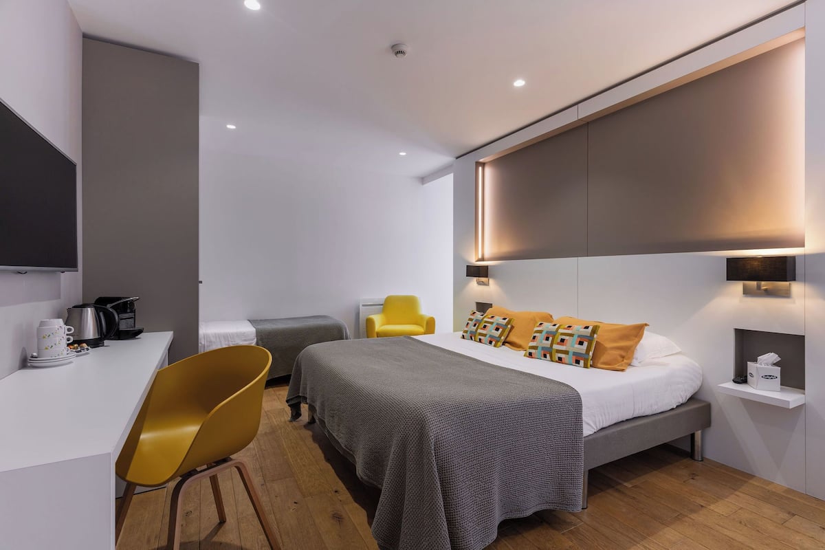 A modern hotel room with a bed, a desk, a chair, and a flat-screen TV.