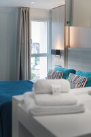 Une chambre d’hôtel avec un lit, une fenêtre avec des rideaux, une lampe de chevet et une vue sur l’extérieur.
