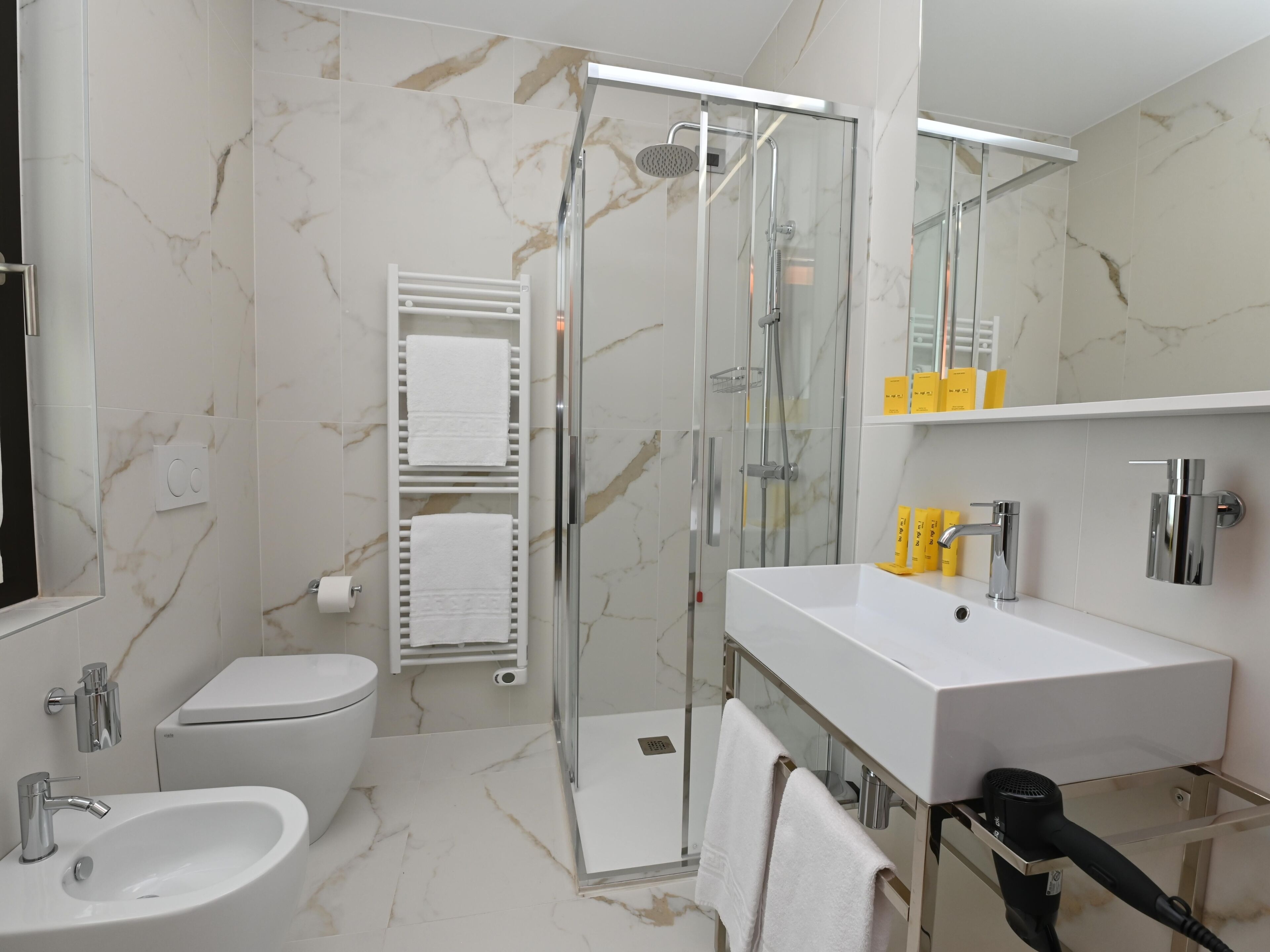 A modern bathroom with a glass-enclosed shower, a white sink, and a toilet.