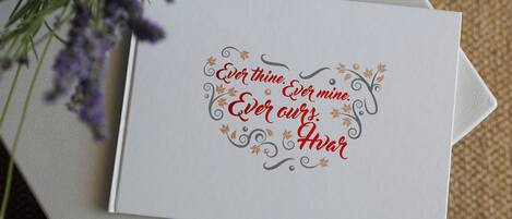 A white card with decorative text and floral designs, placed on a textured surface.