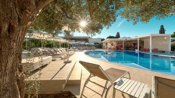 Ein Poolbereich mit Liegestühlen, einem Pool und Sonnenschirmen.