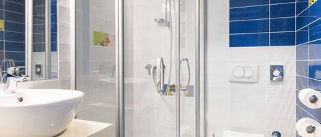 A modern bathroom with a glass-enclosed shower, a white sink, and a toilet.