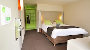 Een hotelkamer met een bed, nachtkastje en een groene deur naar een kast.