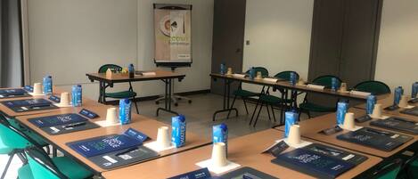 Sala de conferência com mesas, cadeiras, placas de identificação e materiais de boas-vindas.