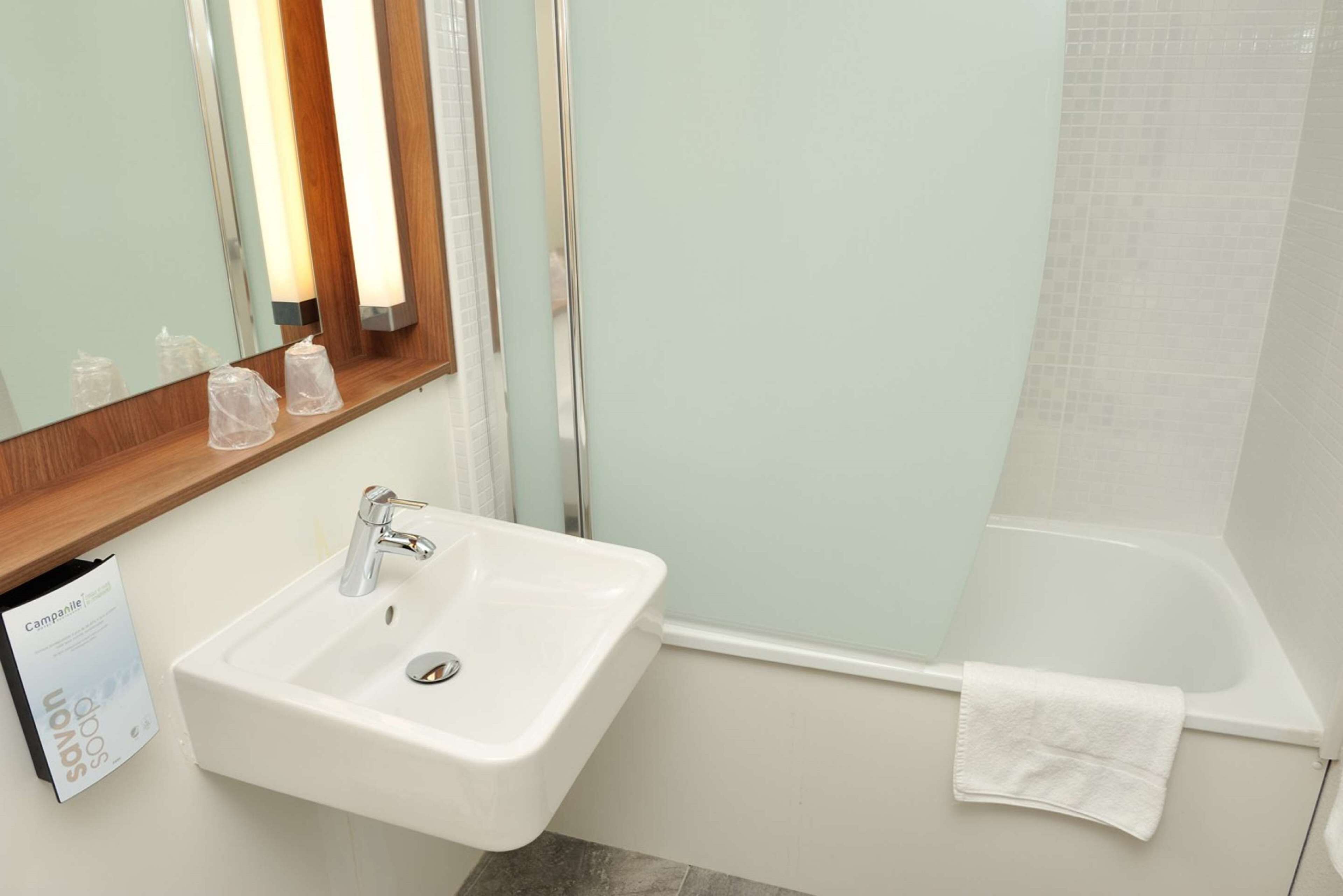 A bathroom with a white sink, a mirror, and a bathtub.