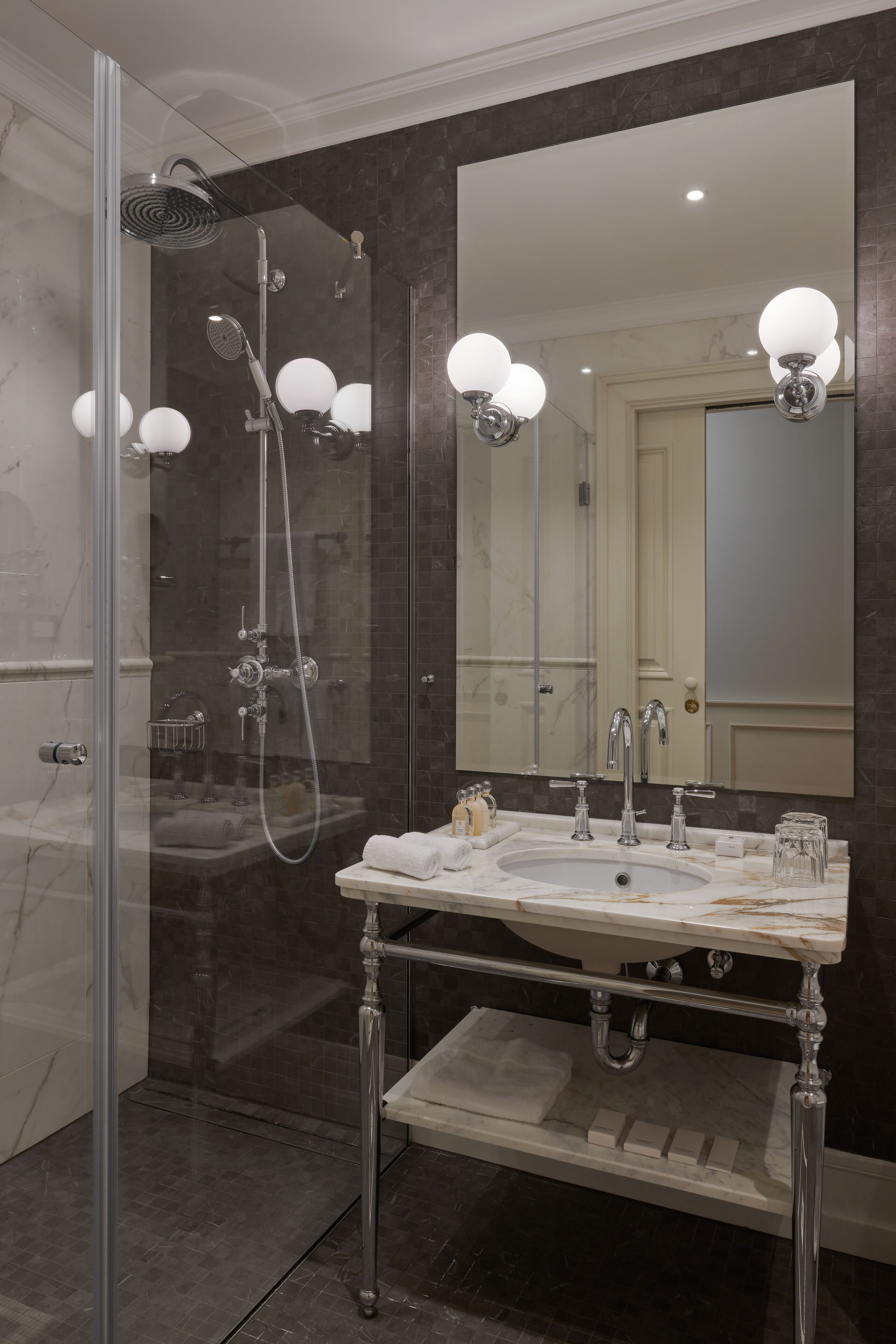 A modern bathroom with a glass-enclosed shower, a marble sink, and a large mirror.