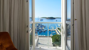En balkon med udsigt over en lysthavn og en fjerntliggende ø.