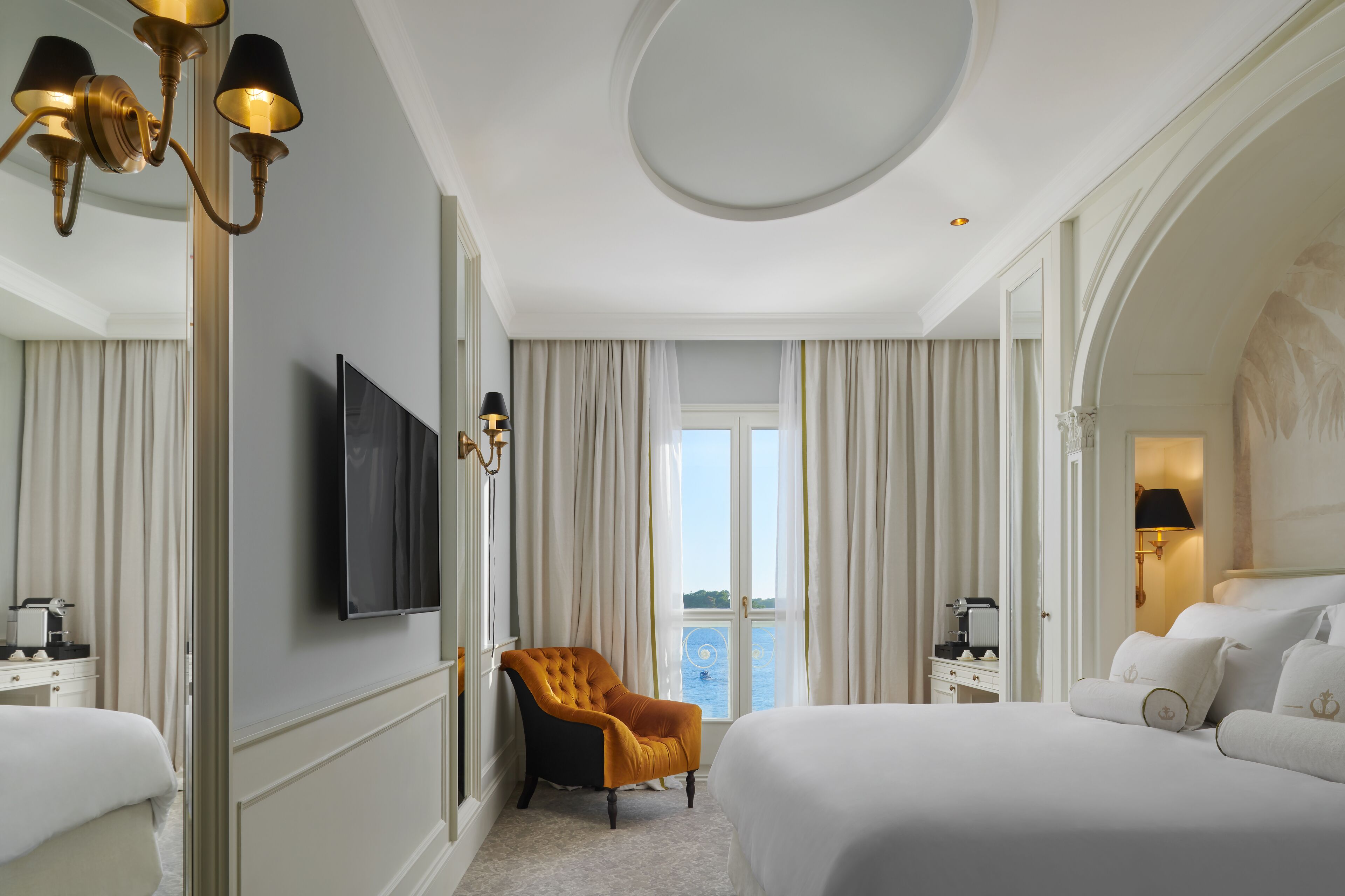 Habitación de hotel con una cama grande, televisión, una silla y vistas al exterior.