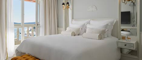 Habitación de hotel con una cama grande, una mesita de noche, un espejo y vista al mar.