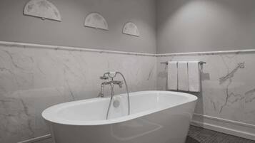 Un baño moderno con una bañera independiente, paredes de mármol y suelo de baldosas.