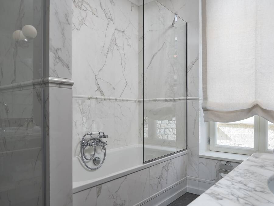 Un baño moderno con ducha de vidrio, bañera independiente y lavamanos de mármol.