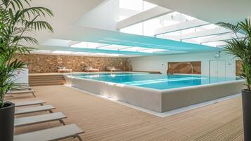 Relax by the rectangular pool surrounded by lounge chairs and a seating area with a table.