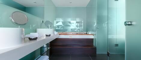 A modern bathroom with a glass shower enclosure, a large mirror, and a vanity with a sink and countertop.