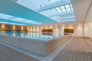 Una piscina techada, sillones reclinables de piscina