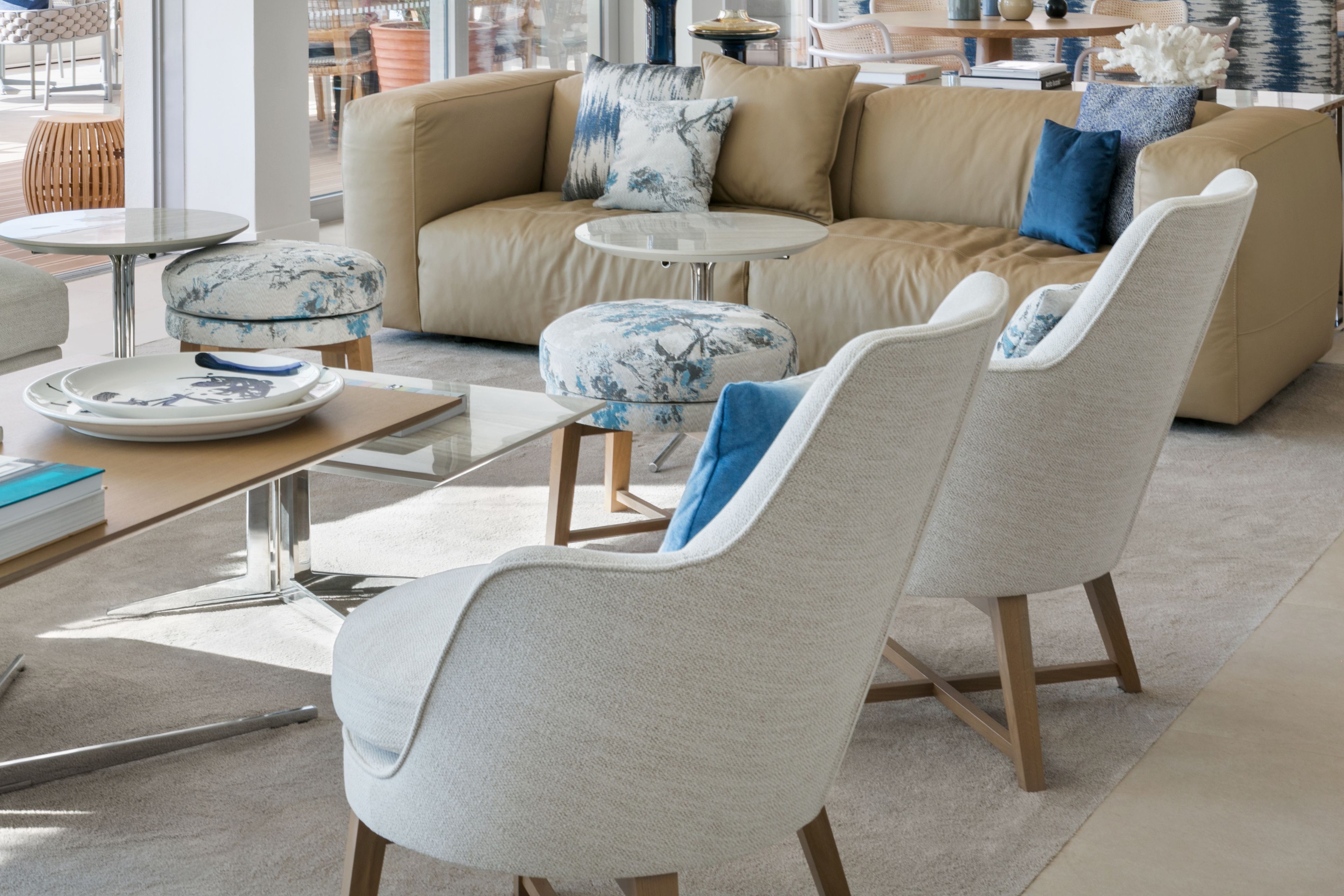 Un salon moderne avec un canapé beige, deux fauteuils, une table basse et une table d’appoint.