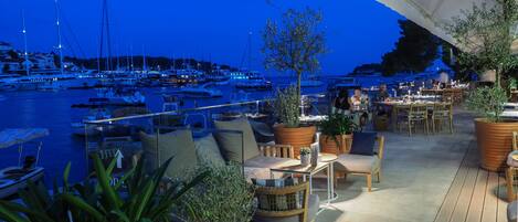 A marina with boats docked, outdoor seating with potted plants, and a view of the water.