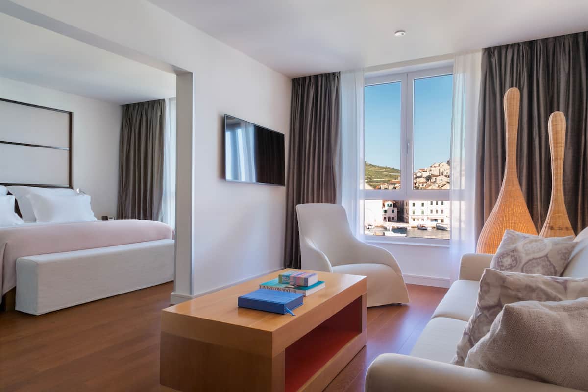 Ein modernes Hotelzimmer mit Bett, Sofa, Fernseher und Blick auf die Stadt.