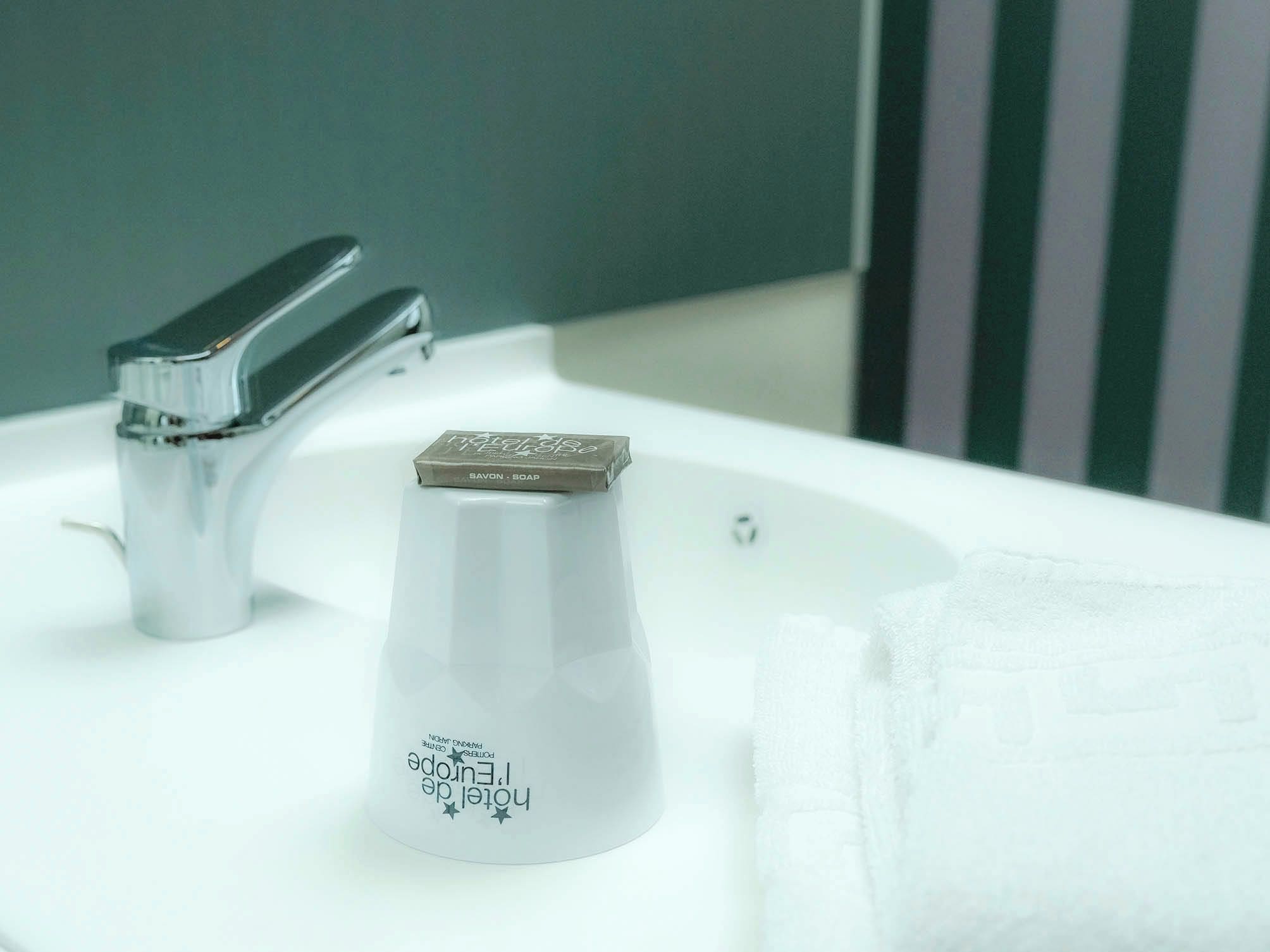 A bathroom with a white sink, a chrome faucet, and a soap dispenser.