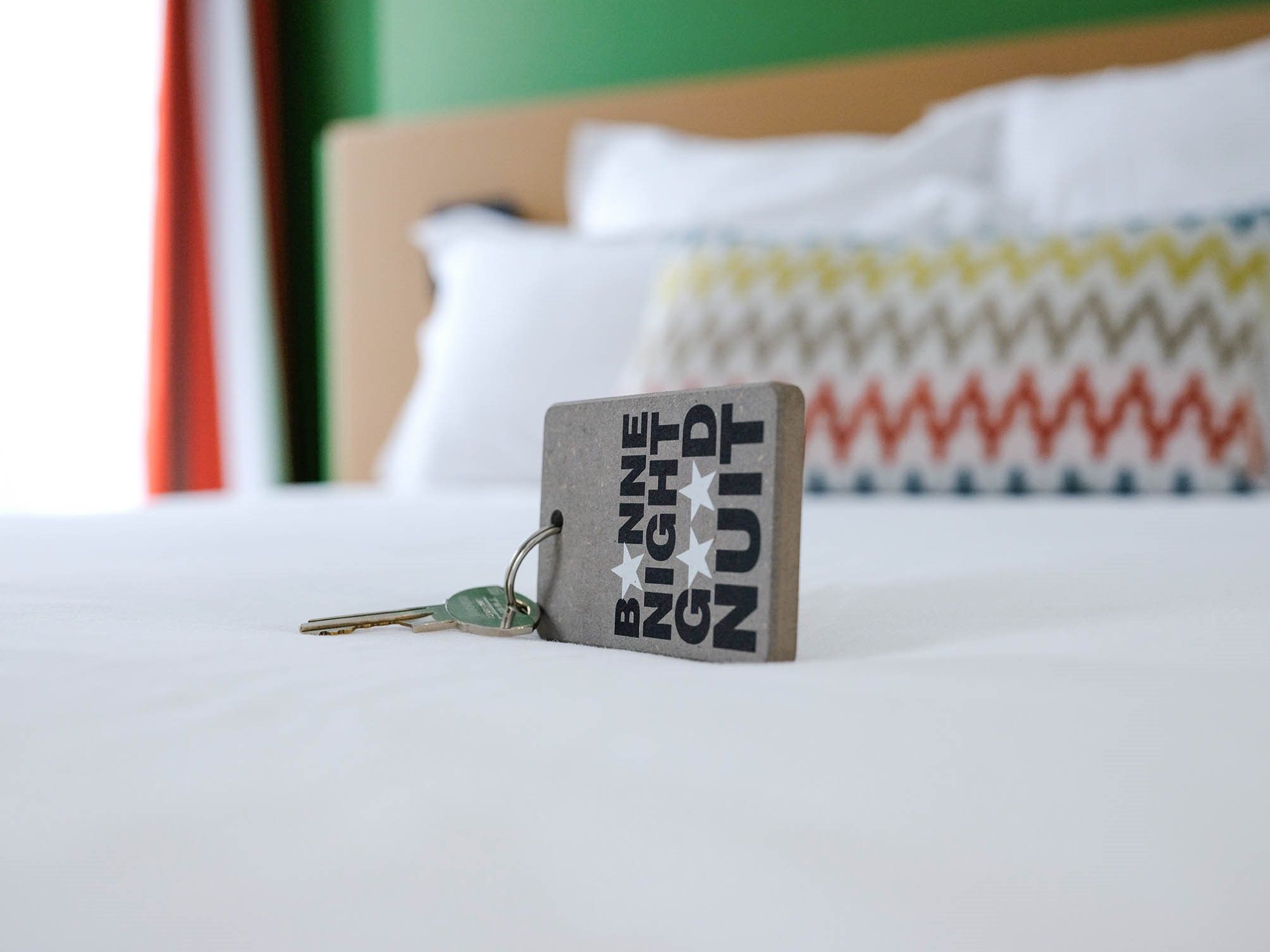 Una cama con un almohadón y una funda decorativa con estampado en zigzag.