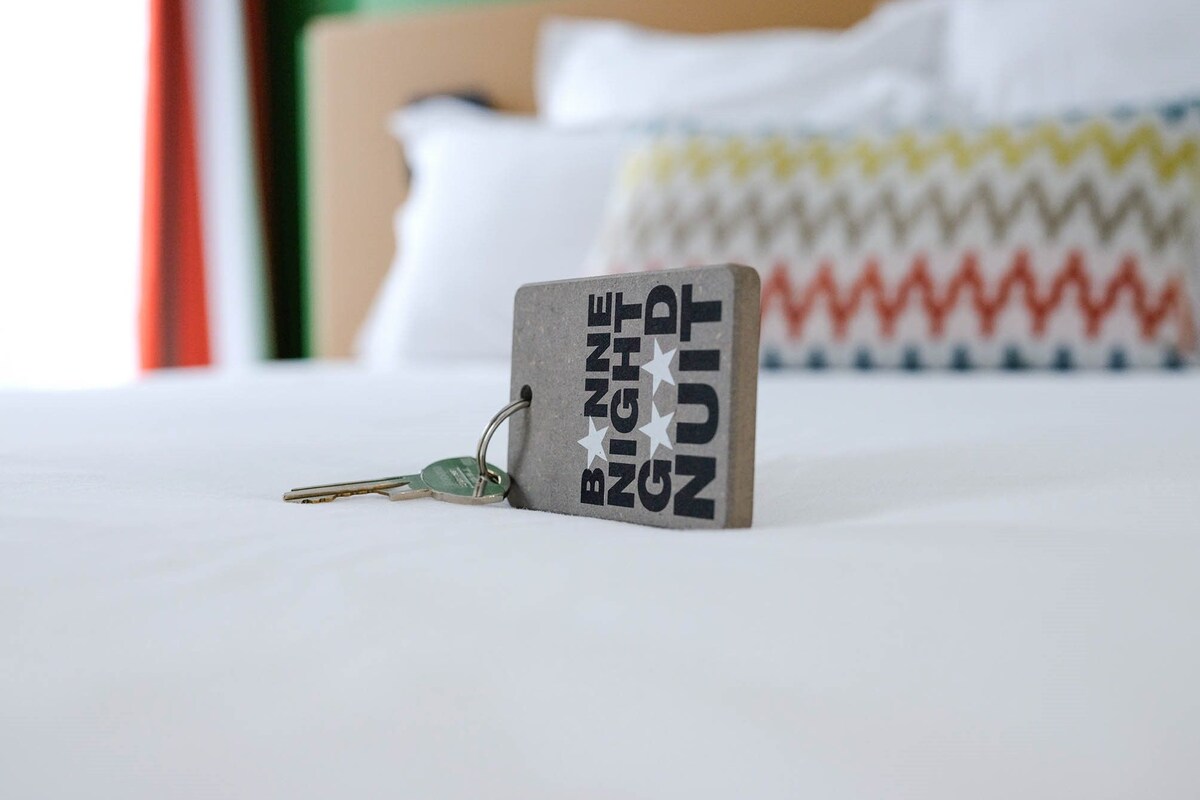 Una cama con un almohadón y una funda decorativa con estampado en zigzag.