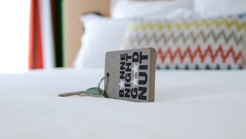 Una cama con un almohadón y una funda decorativa con estampado en zigzag.
