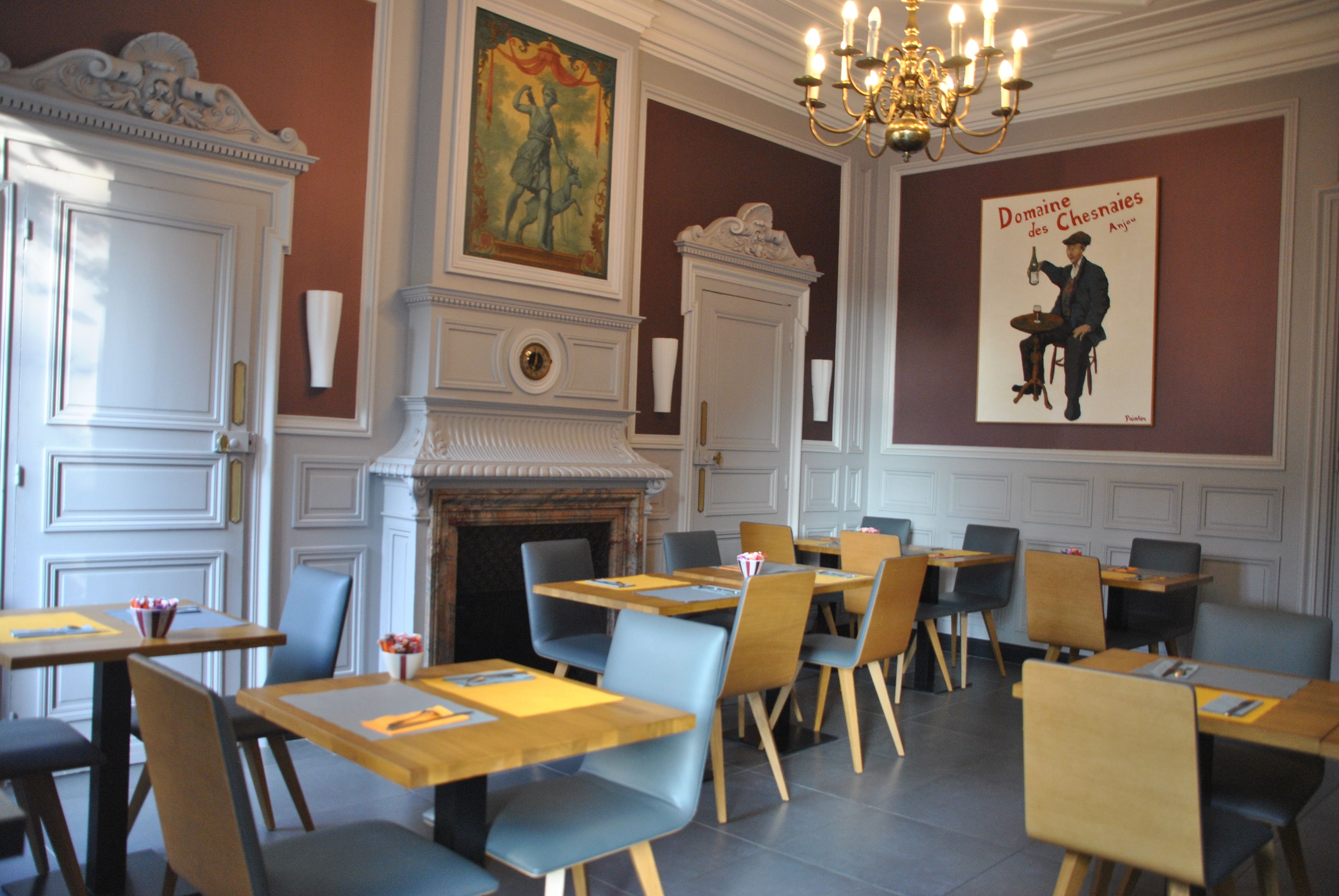 Un comedor con mesas y sillas de madera, chimenea y candelabro.