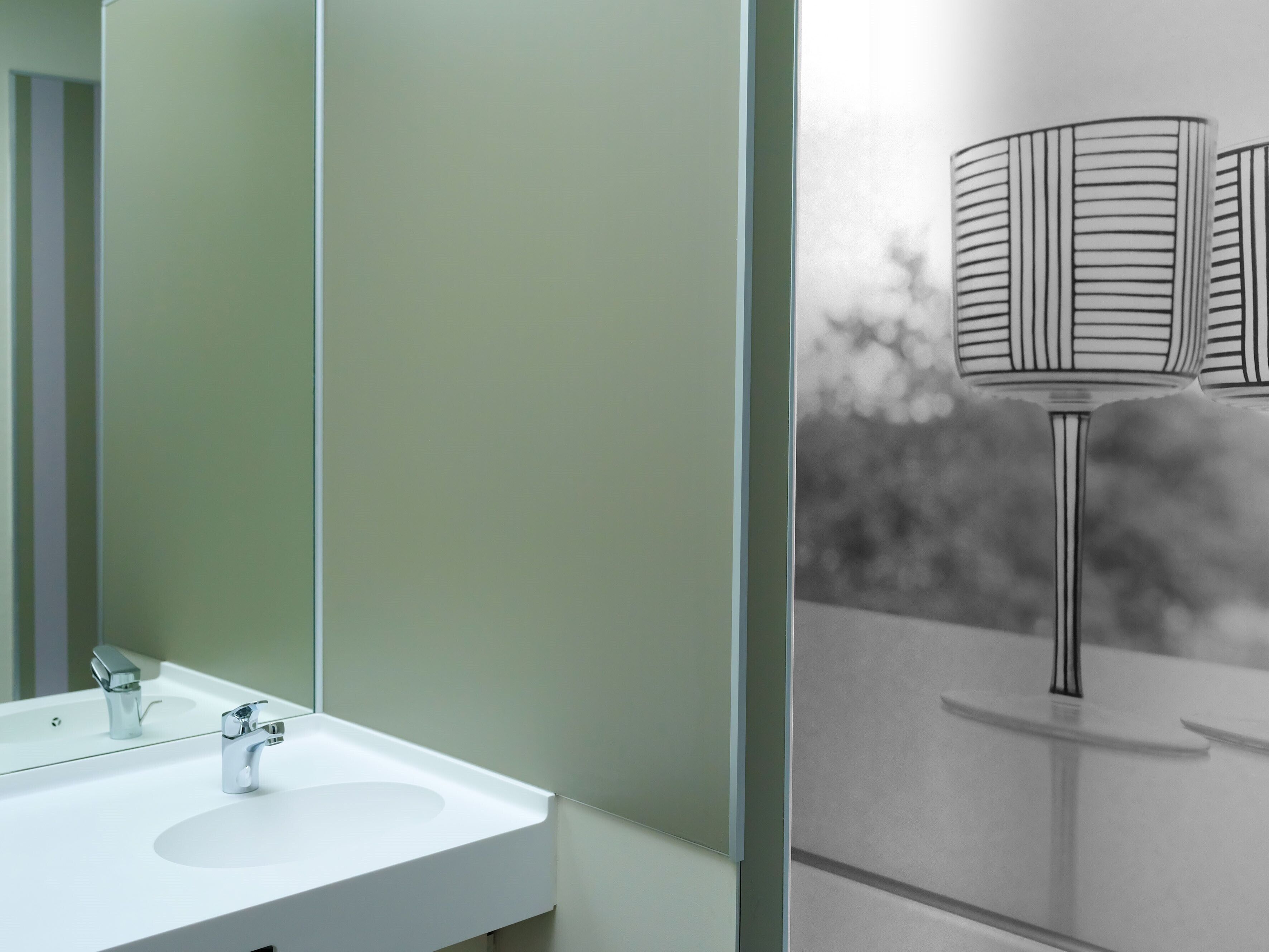 A bathroom with a white sink, a mirror, and a wall-mounted lamp.