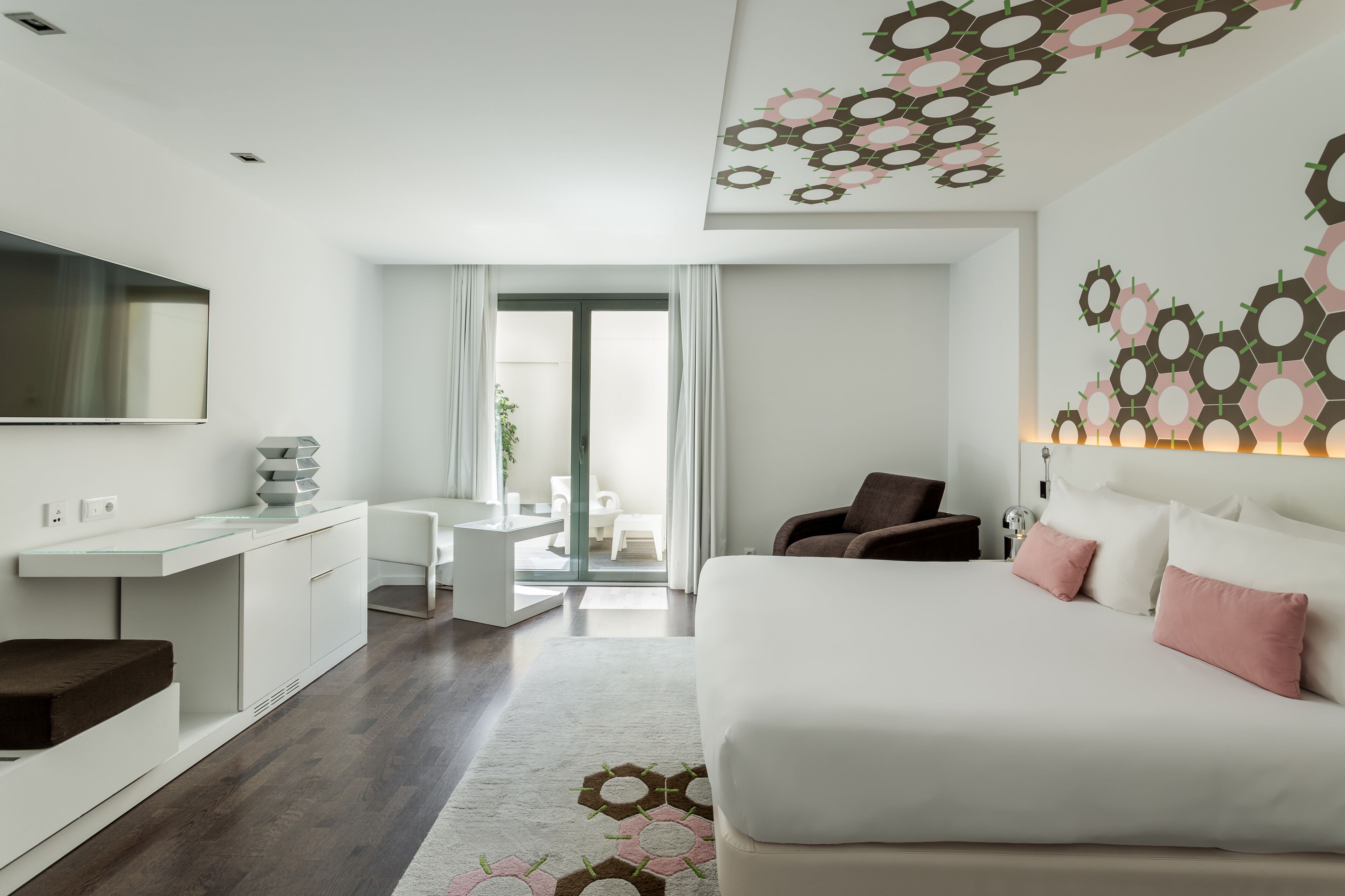 Una habitación de hotel moderna con una cama grande, un escritorio y un televisor.