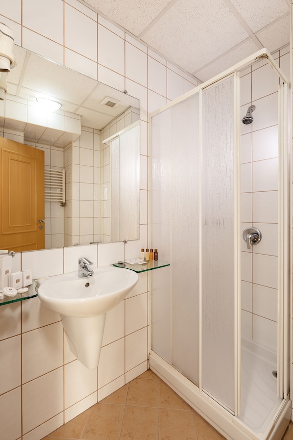 Un baño con lavamanos blanco, espejo y cabina de ducha de vidrio.