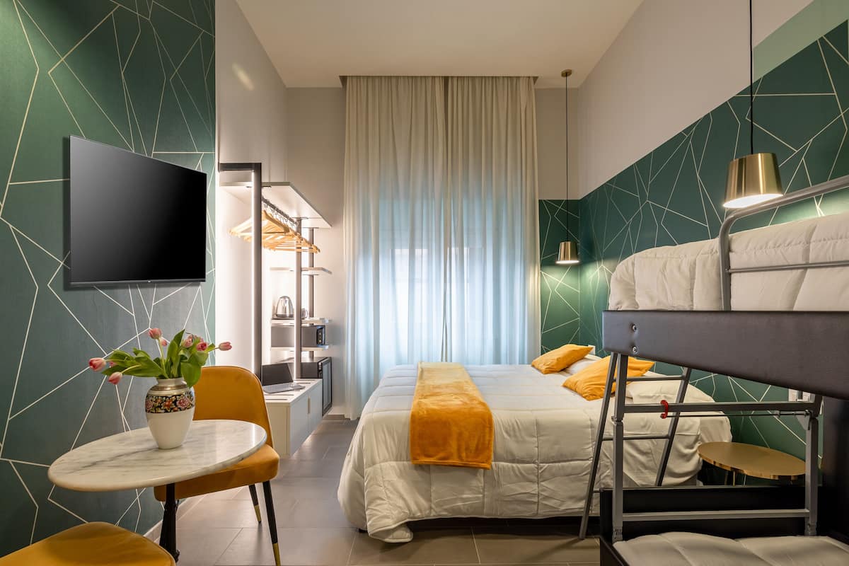 Habitació d'hotel amb un llit, televisió, escriptori, cadira, taula i un ram de flors.