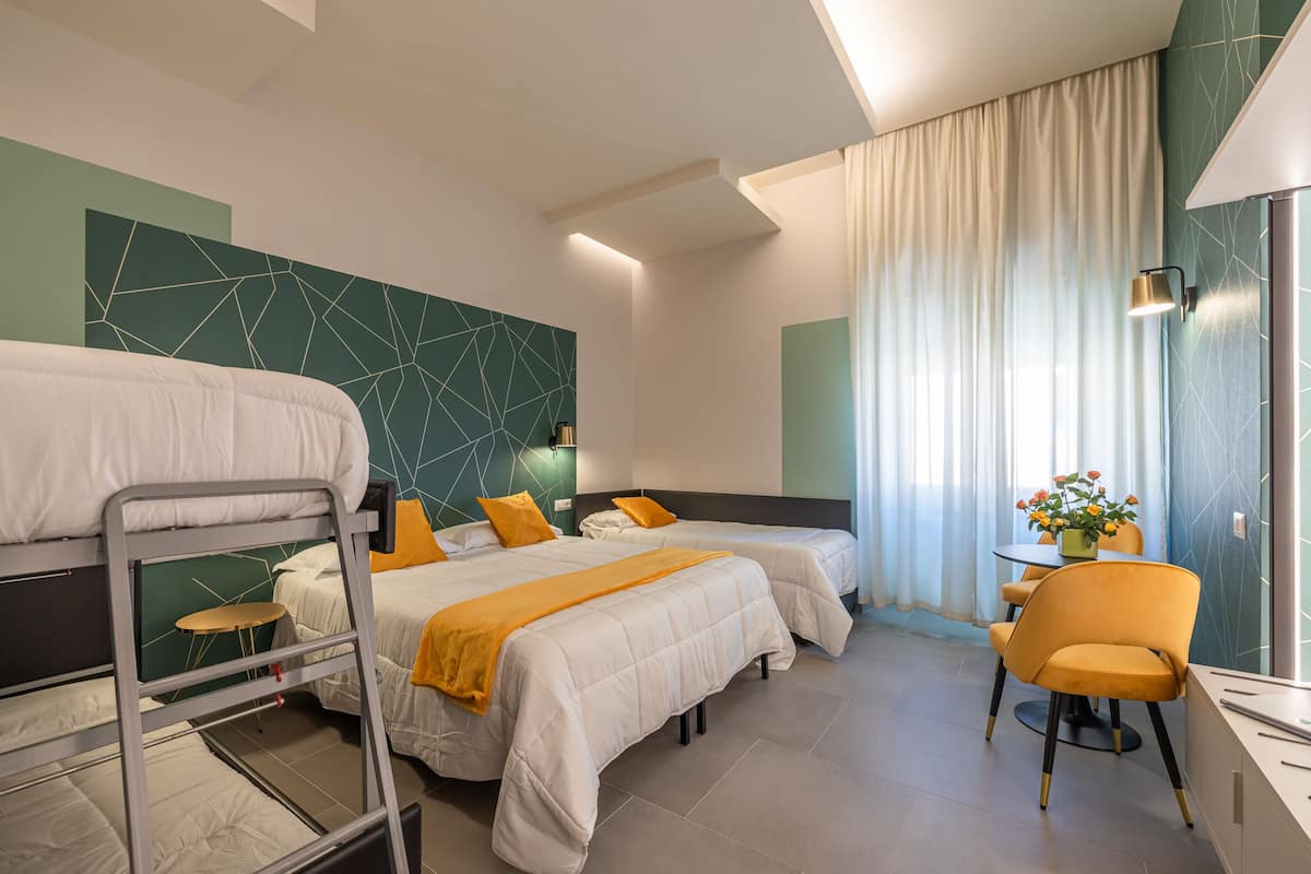 Ein Hotelzimmer mit zwei Betten, einem Schreibtisch, einem Stuhl und einem Vorhangfenster.