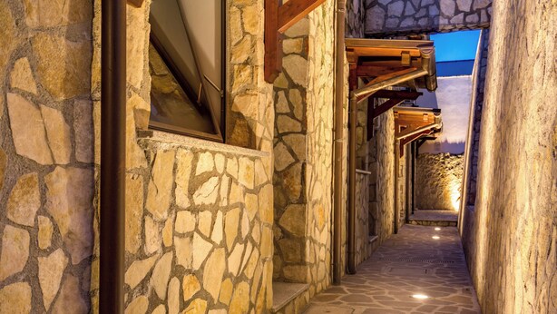 A stone pathway leading to a building with a stone facade and wooden beams. - The Strand Hotel (Rome)
