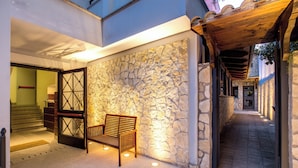 A stone wall with a wooden bench and a door leading to a staircase. - The Strand Hotel (Rome)
