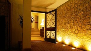 A hallway with a stone wall and a wooden door with glass panels. - The Strand Hotel (Rome)