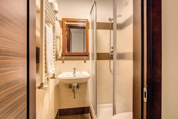 A bathroom with a sink, mirror, and shower. - The Strand Hotel (Rome)