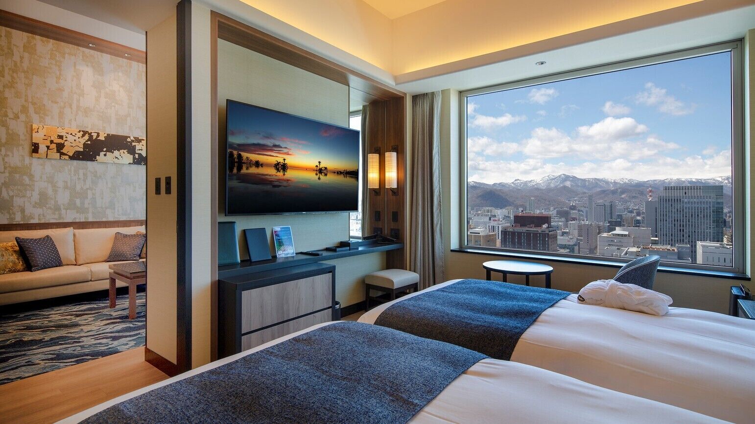 Ein Hotelzimmer mit einem großen Bett, einem Schreibtisch, einem Fernseher und Blick auf die Stadt.