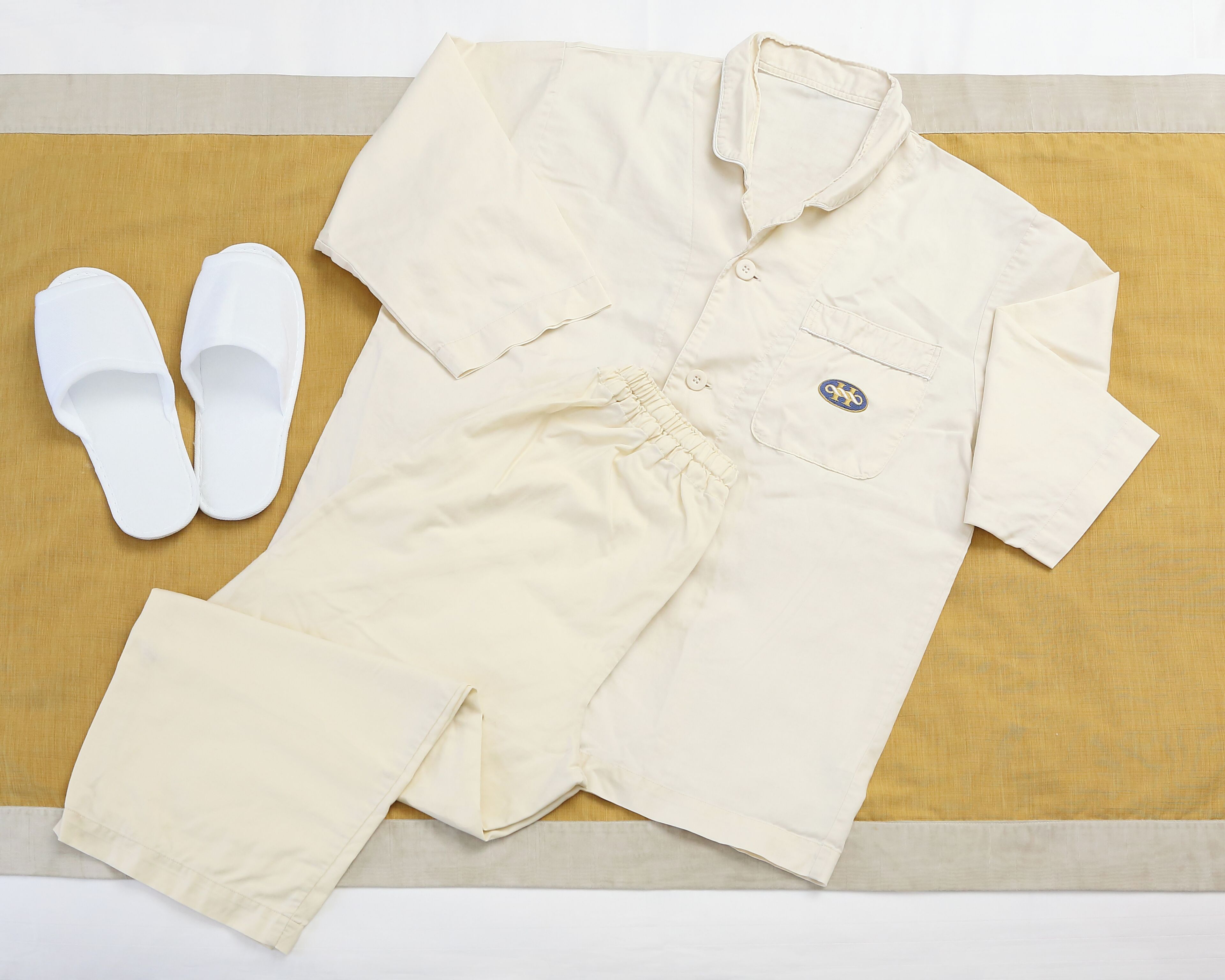 A neatly folded baby onesie and white slippers on a wooden surface.